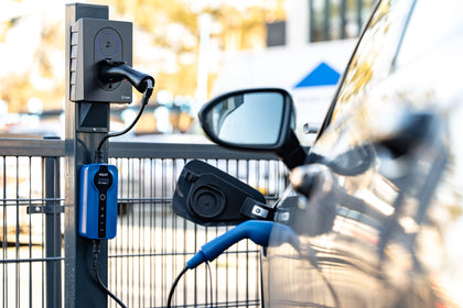 Blue Voldt EV charging cable plugged into a wallbox charger next to a parked electric car