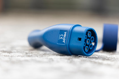 Close-up of a blue Voldt Type 2 EV charging cable connector lying on the ground