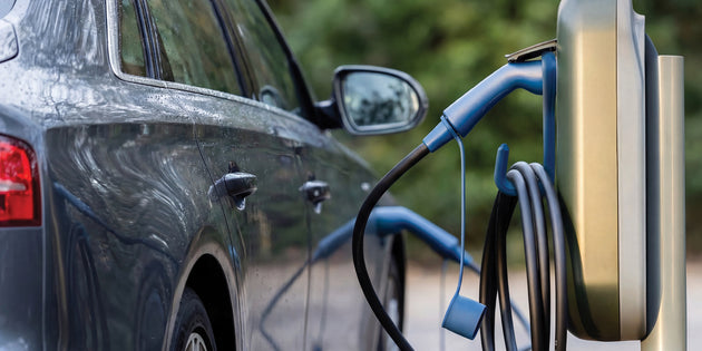 Dark blue Audi charging at a public charging post with a blue Voldt EV charging cable on a hook