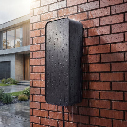 Rain drops on a black outdoor EV cable box fitted to a red brick house wall